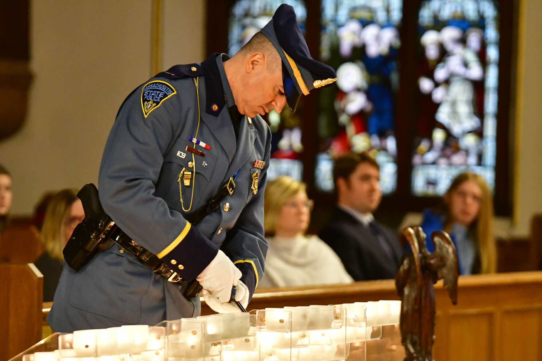 A state police officer lights a candle